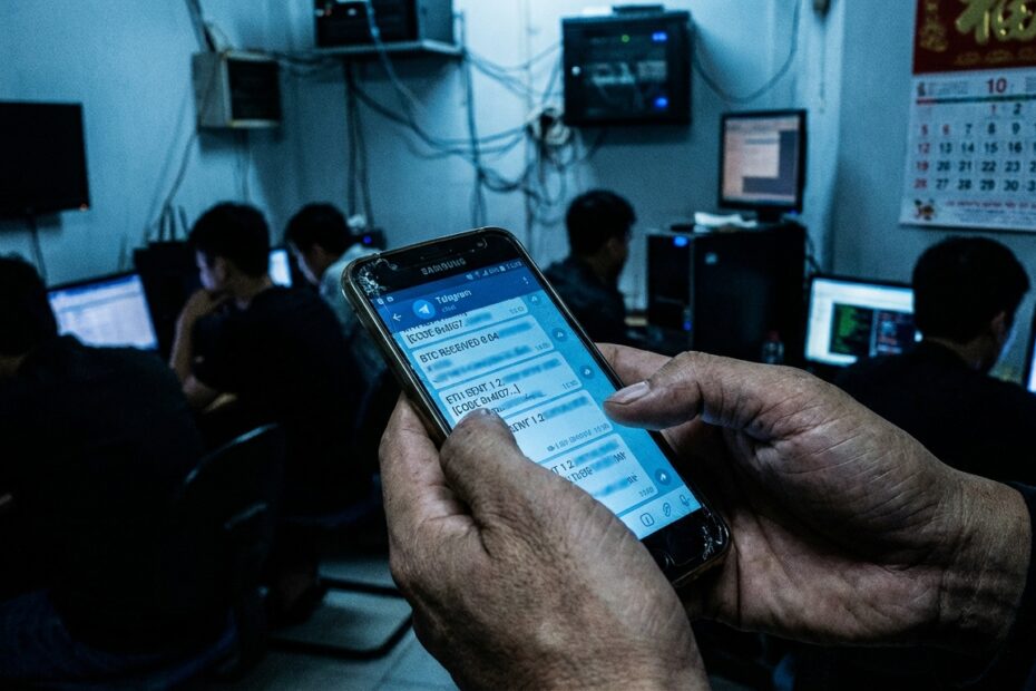 Smartphone exibe transações de criptomoedas em ambiente escuro alusivo a complexos de crimes cibernéticos